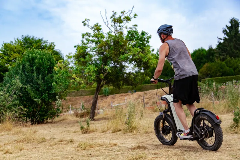 Pilote de trottinette électrique tout-terrain de dos sur les pistes de Bellême.