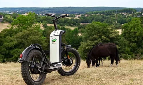 Zoom sur une trottinette électrique tout-terrain de la marque française Zosh face aux paysages vallonnés du Perche.